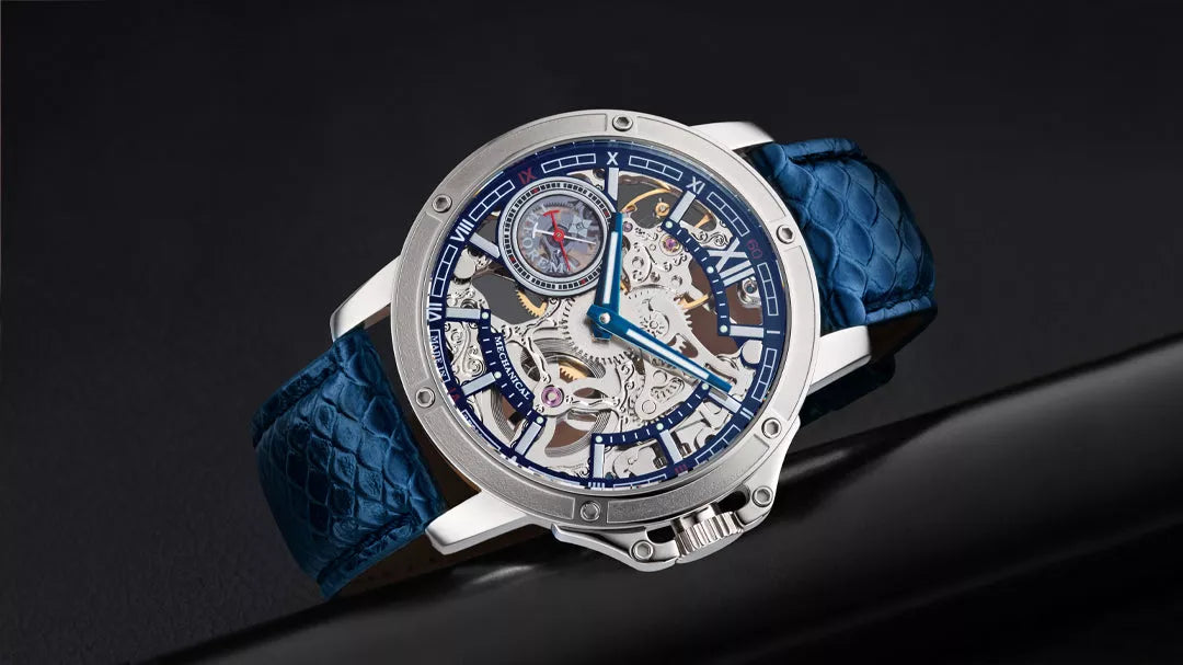 Modern skeleton watch with silver case, blue accents, and textured blue leather strap, displayed on a sleek black surface.