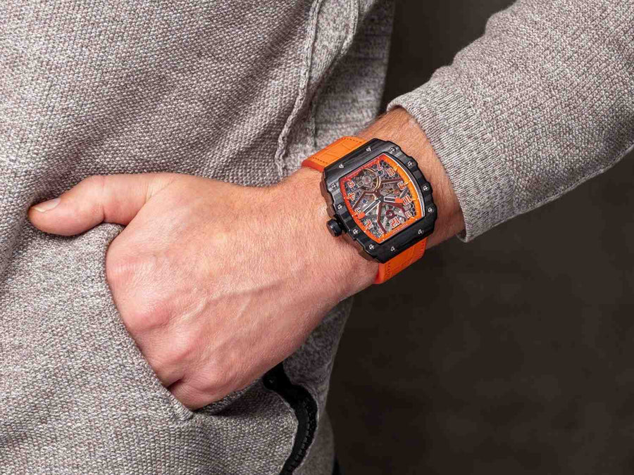 A man's wrist with an orange color watch.
