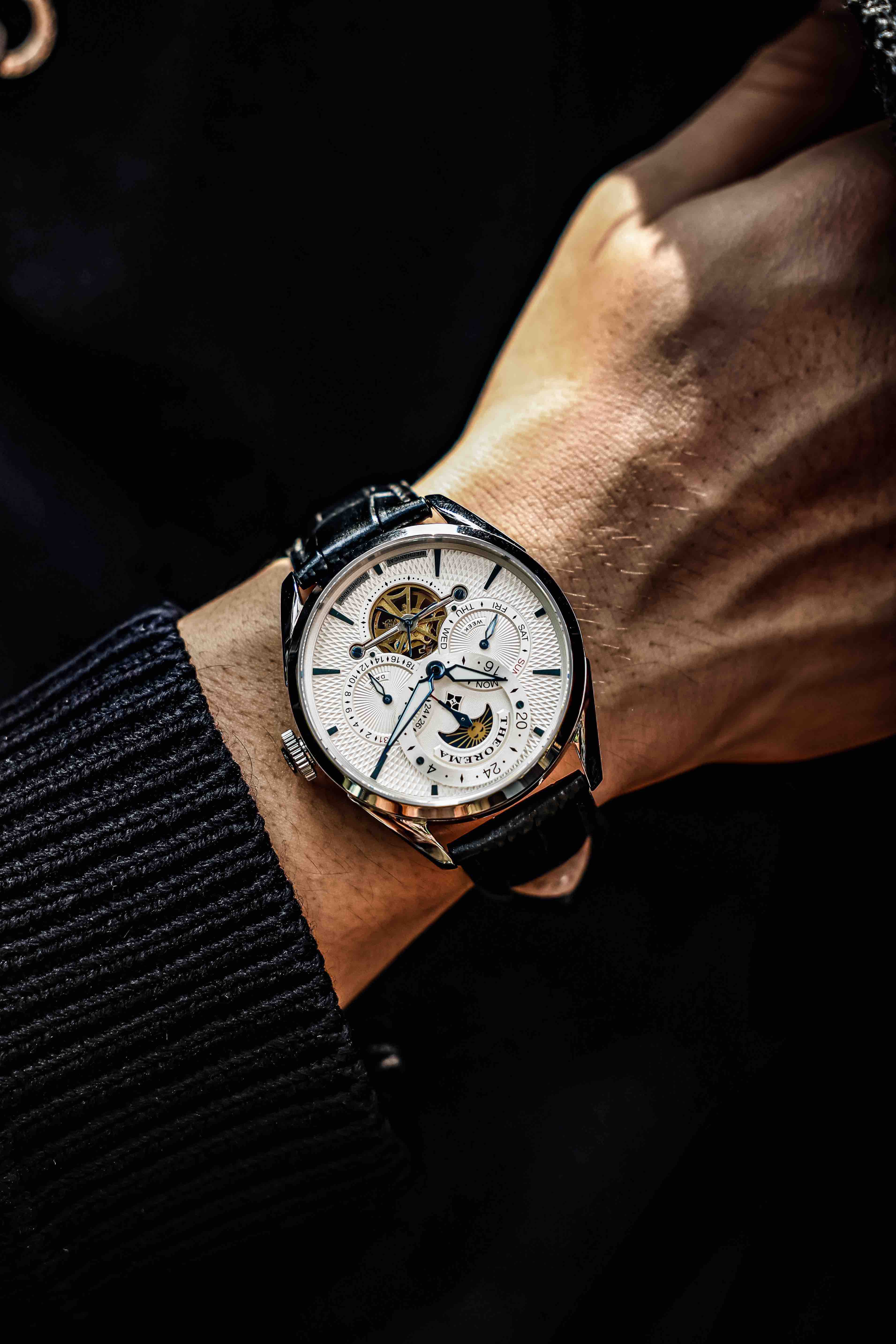 A man's wrist showcasing the Vienna collection white dial with black leather.