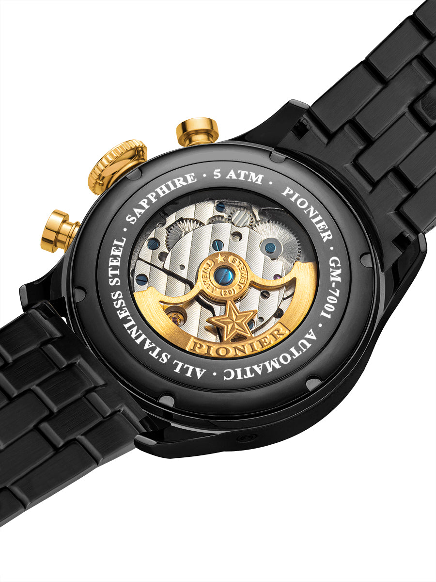 Close-up of a black and gold watch with visible mechanical components on a white background