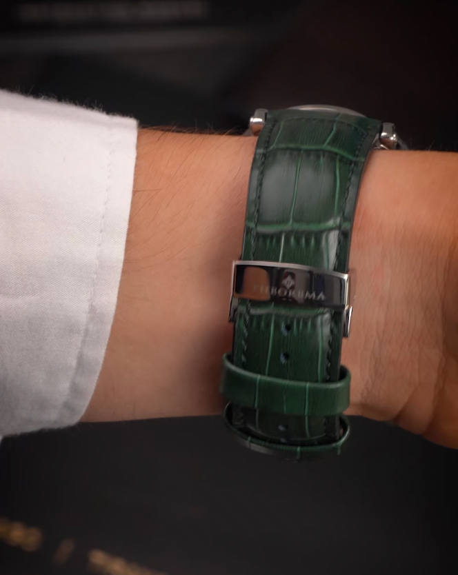 Green watch strap on a wrist with a visible brand logo.